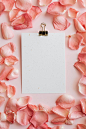 Free Top view of clipboard in pink petals of roses frame arranged on pink table Stock Photo