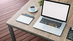MacBook Pro 放在棕色木桌上，旁边是带茶碟的壁纸