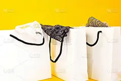 纸工艺品包装与购买的妇女的衣服，其中亚麻伸出。在明亮的黄色背景上