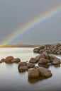 a rainbow shines in the sky over a body of water