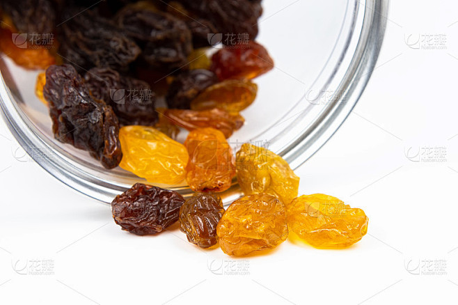 白色背景的塑料罐里的葡萄干和金黄色的葡萄...