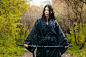 Young asian girl in traditional black kimono with sword against nature background