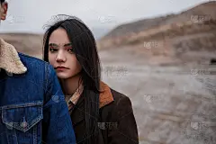 戏剧性的肖像，一个年轻的黑发女孩在多云的天气站在一个男人背后的山的背景。选择性聚焦，聚焦区域小