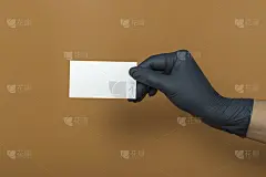 白色名片模型上的彩色背景。一只戴着医用手套的手拿着一张名片