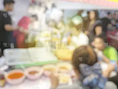 模糊的图像背景，人们在街头的食品餐厅或食品店吃和点一些食物。复古的色调和阳光
