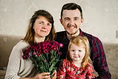 肖像外孙女，父亲，儿子抱着祖母带着鲜花在家微笑，共度时光。国际妇女节。母亲节快乐。节日的概念。一个三