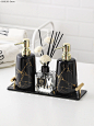 three black and gold bathroom accessories on a white table with flowers in the vases