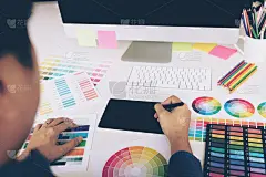 后视图的创意设计师工作在书桌上使用数字图形板和绘图笔在现代家庭办公室。