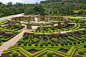 Extensive topiary gardens with many geometric shapes surrounding a rock sculpture