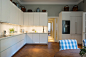 开放式厨房，白色整体橱柜和嵌入式大冰箱。