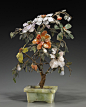 hinese Hardstone Flowering "Jade Tree" 
Chinese hardstone flowering "jade tree"; with large blossoms among lush foliage comprised of carved spinach jade, agate, rose quartz, and others; in a rectangular bowenite jardinière (some flaws)