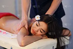 男按摩师为亚洲女孩做背部按摩。放松和滋补按摩