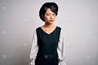 年轻美丽的亚洲女孩穿着休闲服装和帽子站在孤立的白色背景怀疑和紧张，因为问题沮丧皱眉。消极的人。
