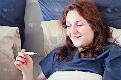 快乐的康复妇女手里拿着温度计。一个被治愈的女孩微笑着躺在床上