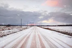 白雪覆盖的乡村道路穿过田野。电线、变压器电杆。车里的全景。五彩的云彩，戏剧性的日落天空。越野，物流，