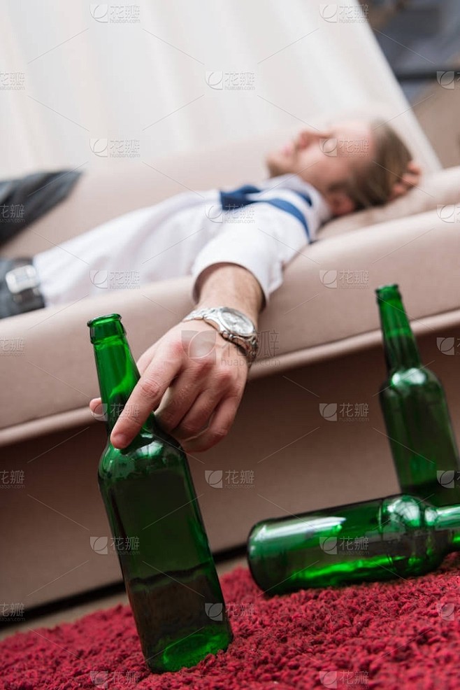 醉酒的人睡在沙发上, 拿着一瓶啤酒