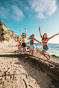 four women jumping in sea shore during daytime