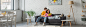 smiling young man hugging girlfriend lying on couch with book in hands in living room, banner