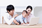 25岁到29岁,三个物体,家庭,斜眼看,可爱的_gic7306947_father and mother using laptop with a baby sitting on table_创意图片_Getty Images China