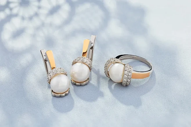 一套银和金戒指和耳环装饰与珍珠在蓝色的背...