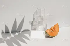 夏季食物静物组成。桌上有哈密瓜水果。白色墙壁与棕榈叶阴影覆盖。空白纸卡片，邀请模型。一杯水，阳光下的
