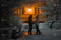 雪夜里，一对年轻的情侣在约会结束后，站在那里互相凝视着对方，说着再见。男朋友陪女朋友回家。侧视图。