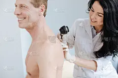 有魅力的年轻皮肤科医生使用皮肤镜在诊所工作