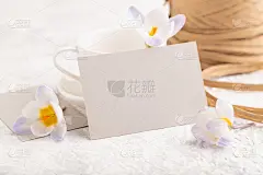 灰色的纸邀请卡，用紫色藏红花雪莲花的模型在灰色的混凝土背景上。空白，侧视，静物，复制空间，婚礼请柬。