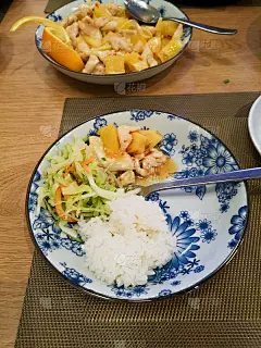 在中餐馆里，青花印花盘子里的中国食物，卷心菜和胡萝卜沙拉，馒头，菠萝和桔子鸡和米饭