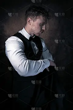 一个留着胡子、卷发、穿着背心、系着领结、远离镜头的帅哥