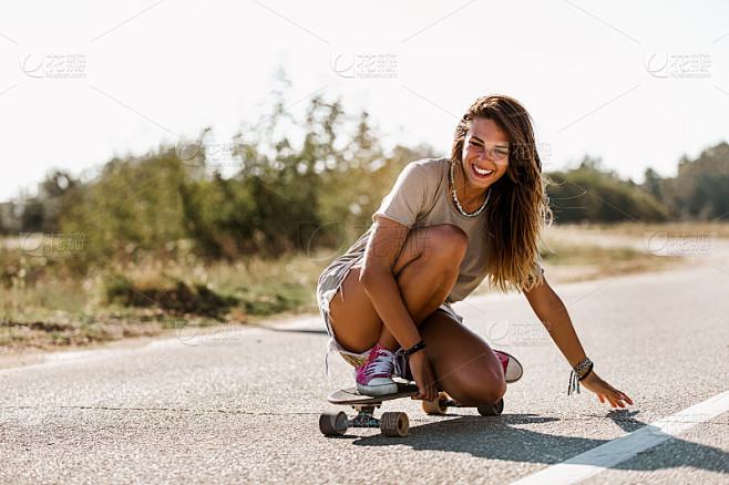 在公路上玩滑板的年轻运动型女子。