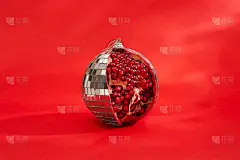 圣诞节的背景。寻常事物的不寻常组合。迪斯科球作为一个水果石榴against一个红色的背景。Copys