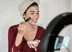 年轻快乐的网红女孩有乐趣拍摄皮肤面膜教程与手机和领导在家里