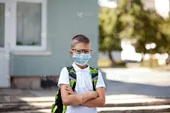 回到学校。戴着眼镜、戴着口罩、背着书包的小男孩保护和安全，免受冠状病毒的侵害。大流行结束后孩子们在上