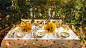 Table dresse avec une nappe au motifs citrons. Assiettes et vgtation assorties au panorama.