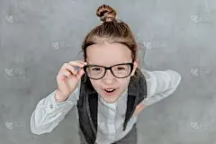 一个小商人女士的特写在一个灰色的背景。穿着眼镜。握着他们的手就是一根商业魔杖。我要去看摄像机。