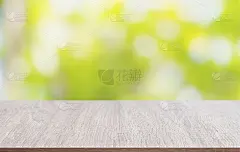 桌面由木材制成，背景是模糊的树叶散景。