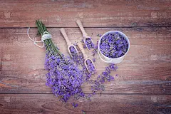 顶视图的碗和木制汤匙与新鲜的薰衣草花和一束薰衣草在一个棕色的木制背景。
