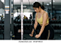 Young Asian woman flexing arm muscles on cable machine at gym.