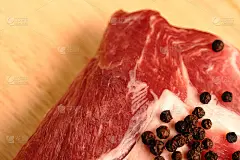 一块木板上放着红肉和胡椒球。可见的脂肪层和肉的质地。猪肉