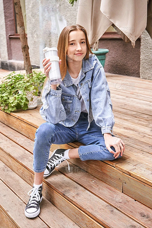 漂亮女孩在户外喝饮料。用自己的杯子买外卖咖啡。真实的人素材花瓣网