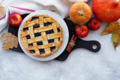 木桌上放着浆果馅饼和橘色南瓜