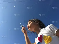 一个小女孩在吹蒲公英的种子。