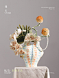 This may contain: a vase filled with flowers sitting on top of a white tablecloth covered table next to a gray wall