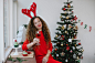 Positive woman in stylish outfit sitting with glass of champagne in Christmas room