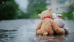 忠实的朋友- -一只兔子和一只小熊并排坐在路上，在倾盆大雨中湿透了。向前看，拥抱。后视镜