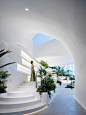 interior shot of massive restaurant with undulating white surfaces and a forest of plants and curvy staircase