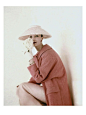 Vogue - March 1956 Model Evelyn Tripp wearing pink ensemble; wool tweed raglan coat by Zelinka-Matlick and straw hat by Dior-New York. Also wearing Bobley bracelets, pink earrings, white short gloves, and holding white flowers.
