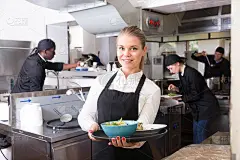 厨房里的女服务员拿着做好的饭菜