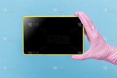 一只戴着粉色医用手套的女性手拿着一个蓝色背景上的空白现代平板电脑。模拟，名片